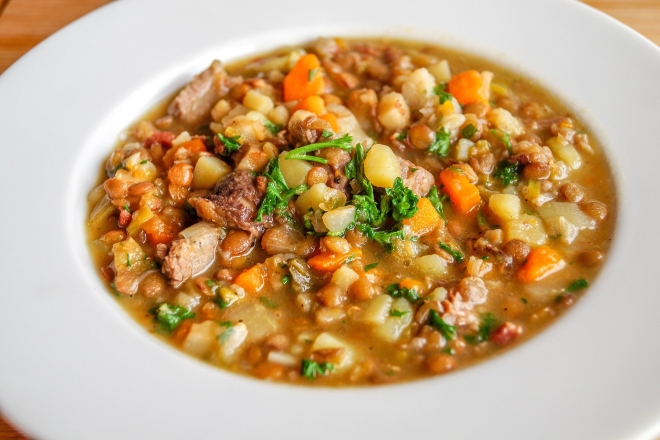 Weißer tiefer Teller, der mit einer Linsensuppe gefüllt ist. 