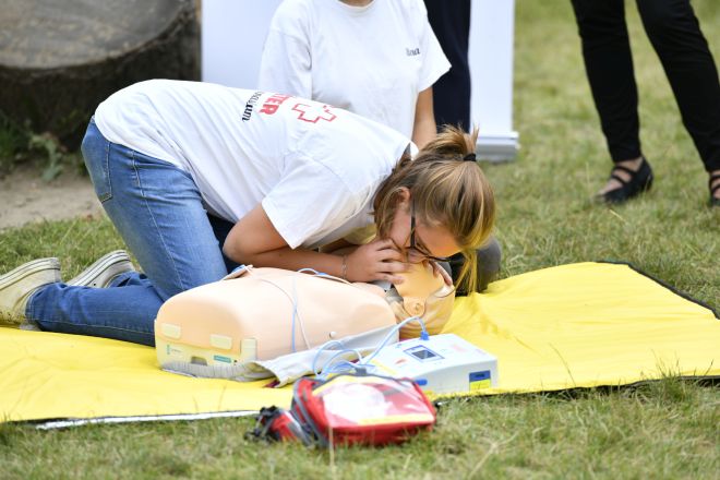 Junges Mädchen bei einer Erste Hilfe Übung. Sie kniet über einem Dummy und führt eine Atemspende aus. 