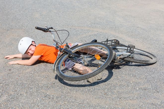 Fahrradsturz. Junge liegt unter seinem Fahrrad am Boden.