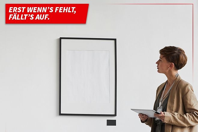 Frau blickt auf einen Bilderrahmen, der an der wand hängt. das Gemälde fehlt. 