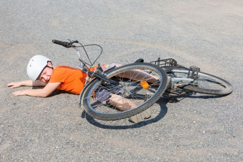 Kind am Boden liegen, darüber das Fahrrad