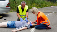 Zwei Ersthelfende knien am Boden bei einer verletzten Person